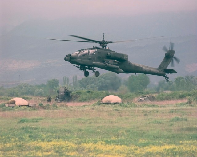 23 Απριλίου 1999 Α/Δ Rinas. Ε/Π Apache σε πτήση εξοικειώσεως. Στο βάθος φαίνονται τα χαρακτηριστικά πολυβολεία της εποχής του Εμβέρ Χότζα (U.S. Air Force photo by Tech. Sgt. Cesar Rodriguez) (RELEASED) 